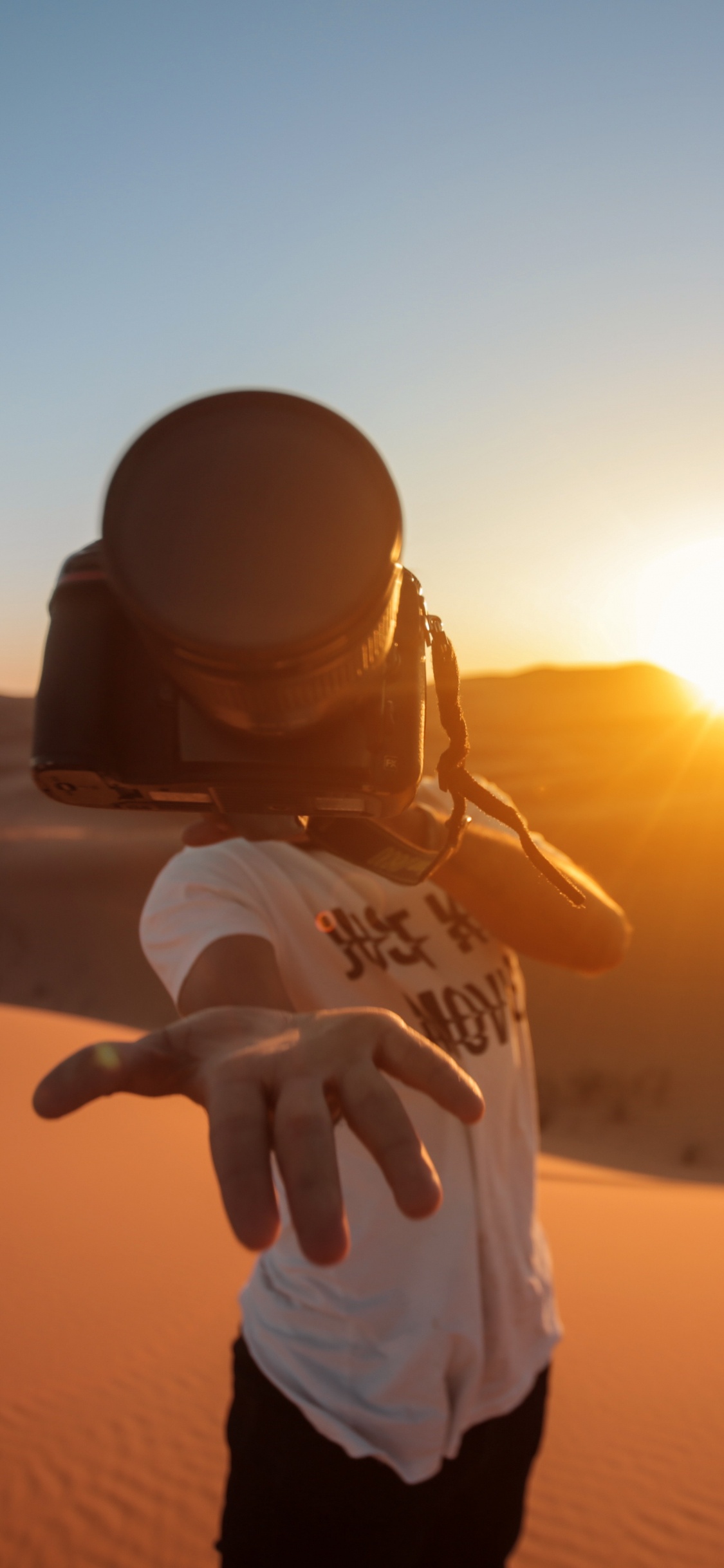 Man in White Shirt and Black Pants Standing on Sand During Sunset. Wallpaper in 1125x2436 Resolution