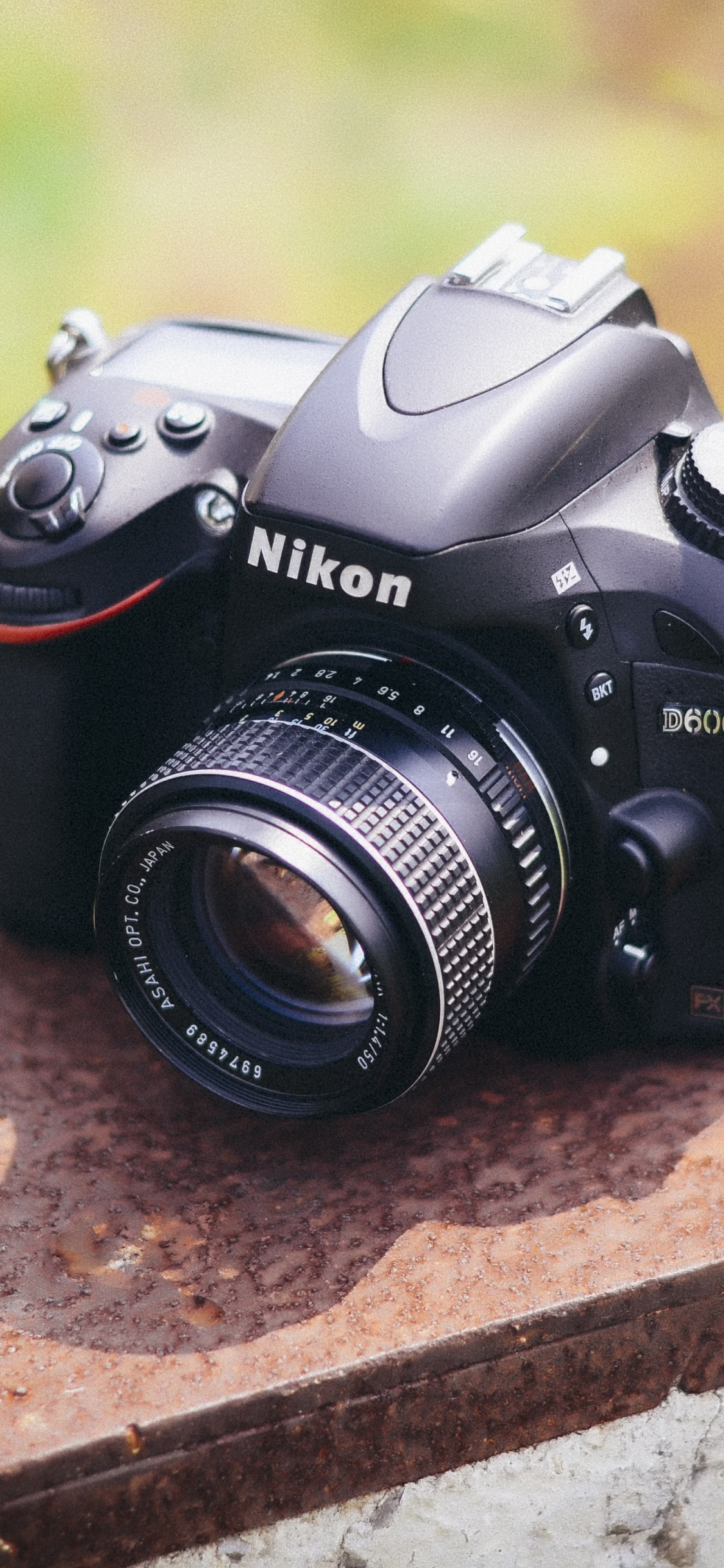 Schwarze Nikon Dslr Kamera Auf Brauner Betonoberfläche. Wallpaper in 1125x2436 Resolution