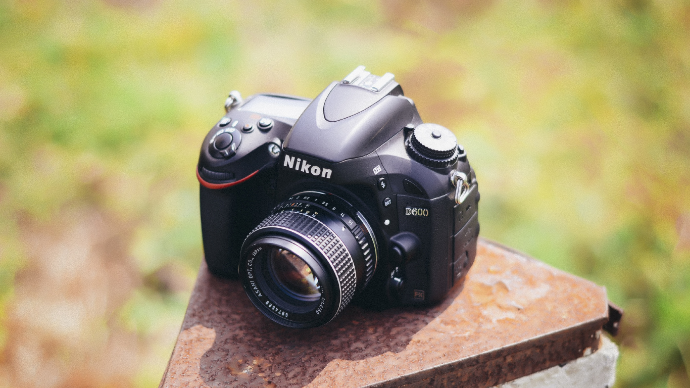 Schwarze Nikon Dslr Kamera Auf Brauner Betonoberfläche. Wallpaper in 1366x768 Resolution