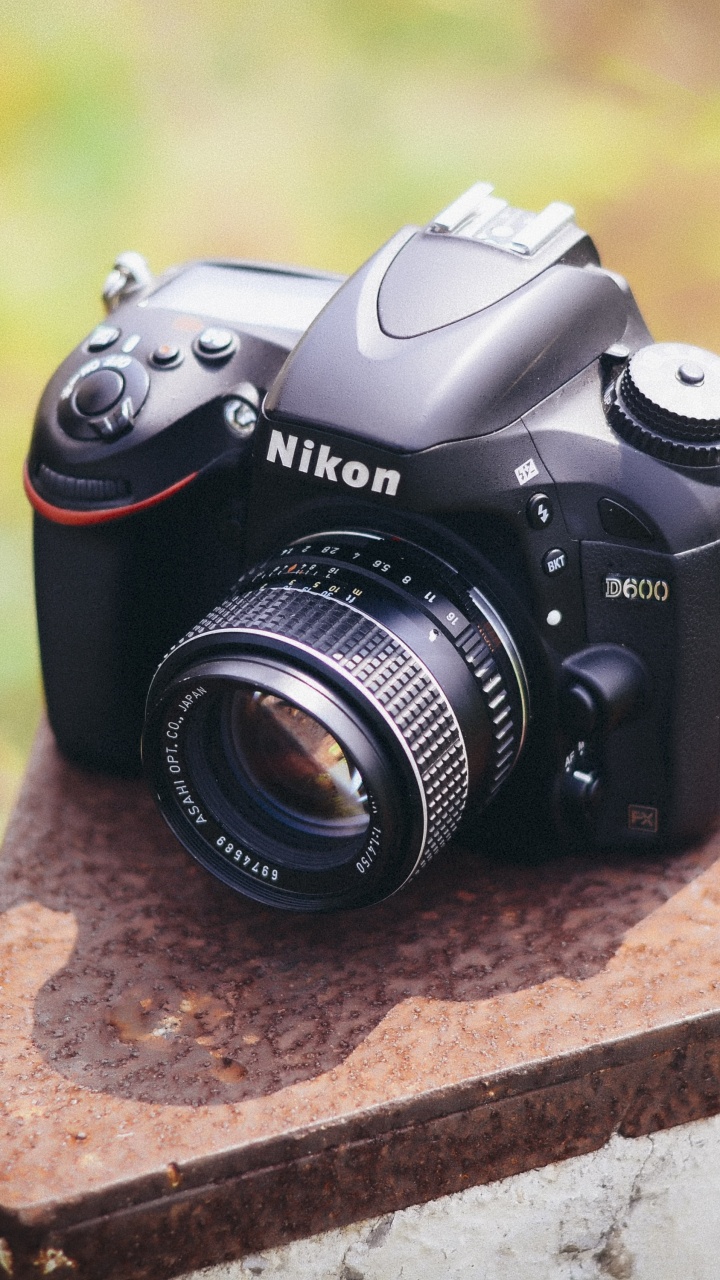 Schwarze Nikon Dslr Kamera Auf Brauner Betonoberfläche. Wallpaper in 720x1280 Resolution