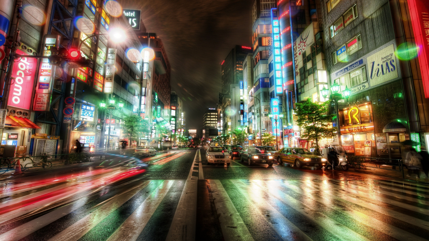 Autos Auf Der Straße Zwischen Hochhäusern Während Der Nacht. Wallpaper in 1366x768 Resolution