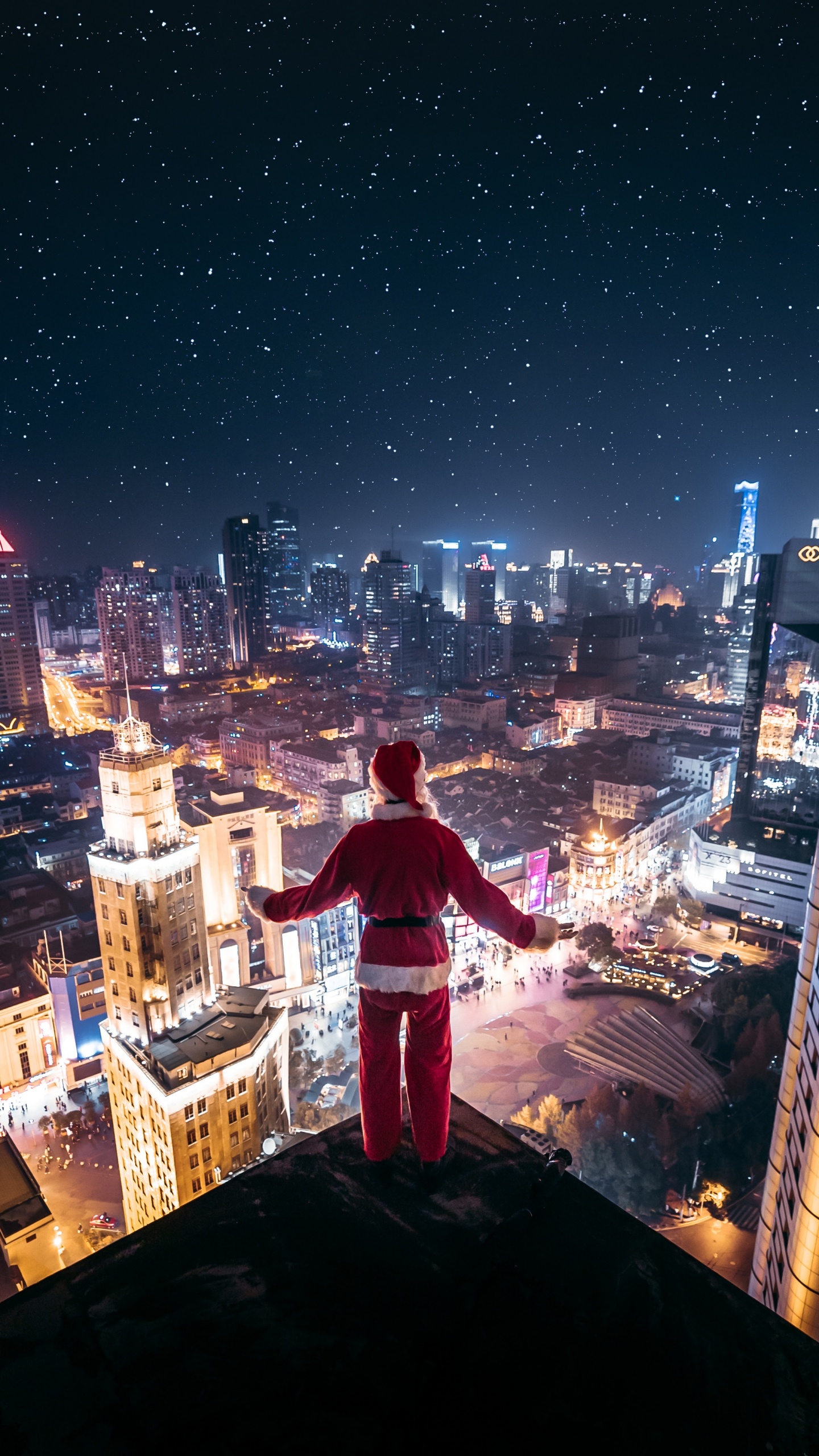 Hombre Con Camisa Blanca y Roja Sentado en el Borde Del Edificio Durante la Noche. Wallpaper in 1440x2560 Resolution