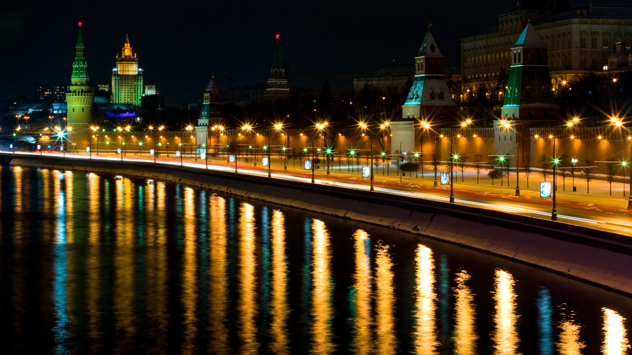 Edificios de la Ciudad Iluminados Cerca Del Cuerpo de Agua Durante la Noche.. Wallpaper in 1280x720 Resolution