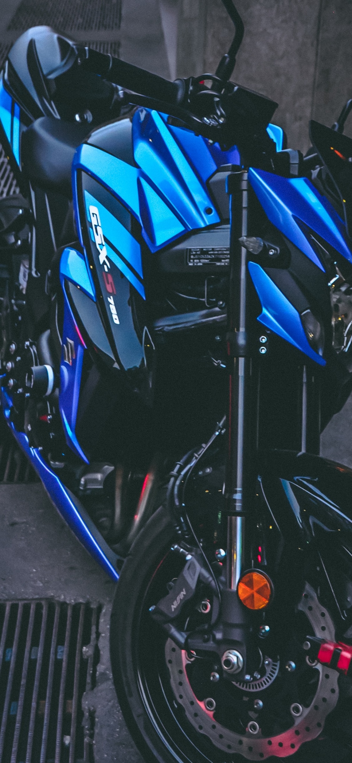 Blaues Und Schwarzes Motorrad Auf Grauem Betonpflaster Geparkt. Wallpaper in 1125x2436 Resolution
