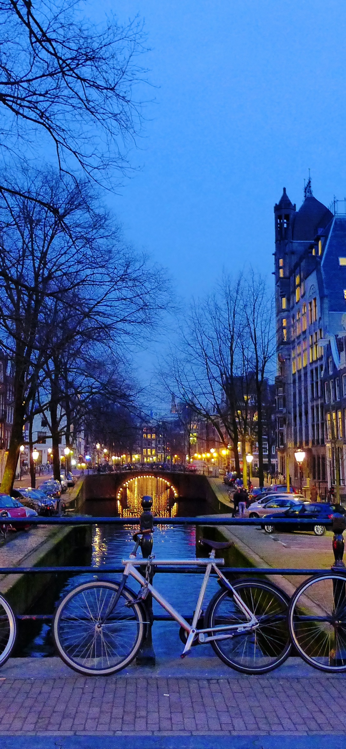 Fahrräder, Die Nachts Auf Dem Bürgersteig in Der Nähe Des Gebäudes Geparkt Sind. Wallpaper in 1125x2436 Resolution
