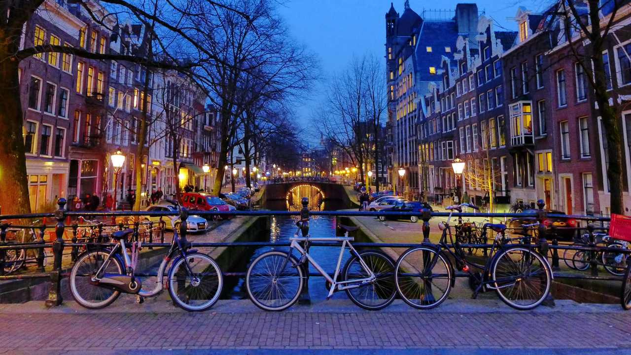 Bicicletas Estacionadas en la Acera Cerca Del Edificio Durante la Noche. Wallpaper in 1280x720 Resolution