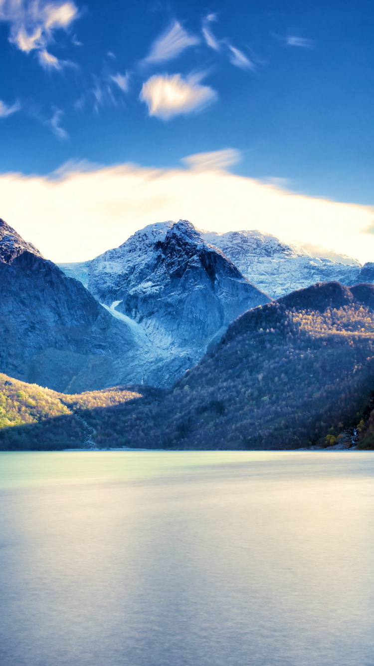 Grüne Und Weiße Berge Neben Gewässer Unter Blauem Himmel Tagsüber. Wallpaper in 750x1334 Resolution