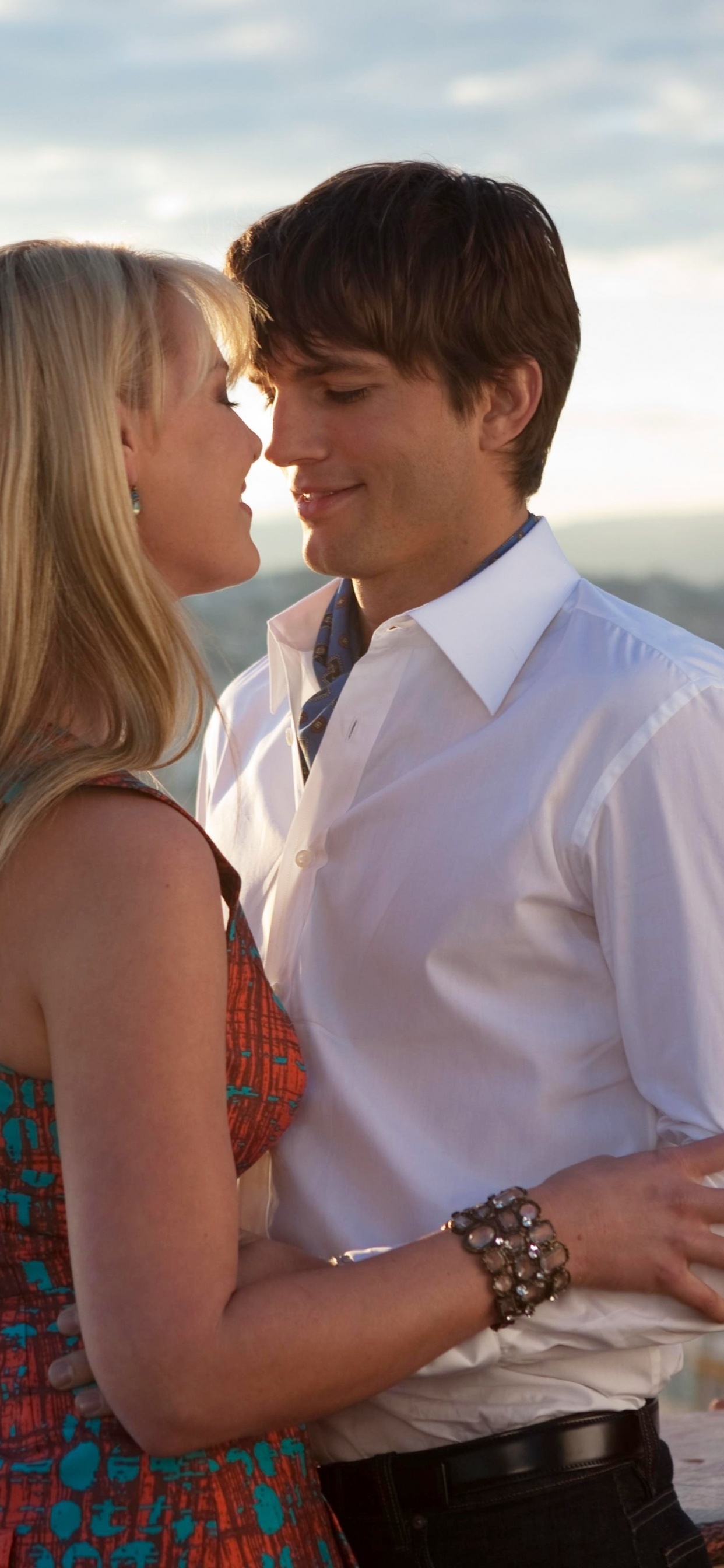 Man in White Suit Kissing Woman in Red and Blue Sleeveless Dress. Wallpaper in 1242x2688 Resolution