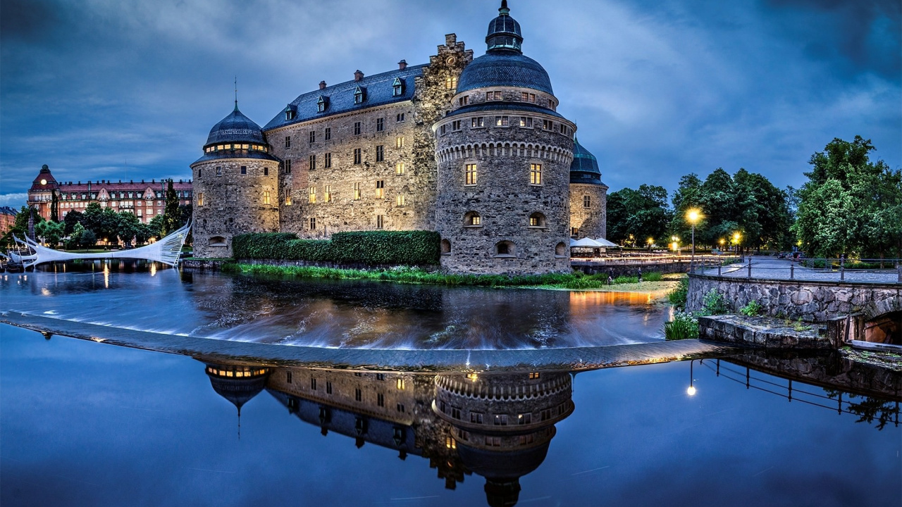 Edificio de Hormigón Marrón Cerca Del Cuerpo de Agua Durante la Noche. Wallpaper in 1280x720 Resolution