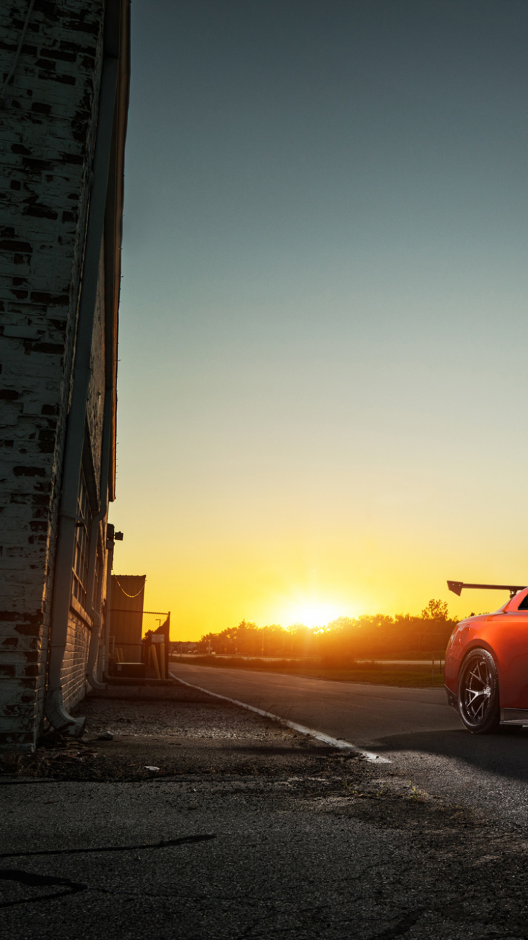 Rote Limousine Unterwegs Bei Sonnenuntergang. Wallpaper in 750x1334 Resolution