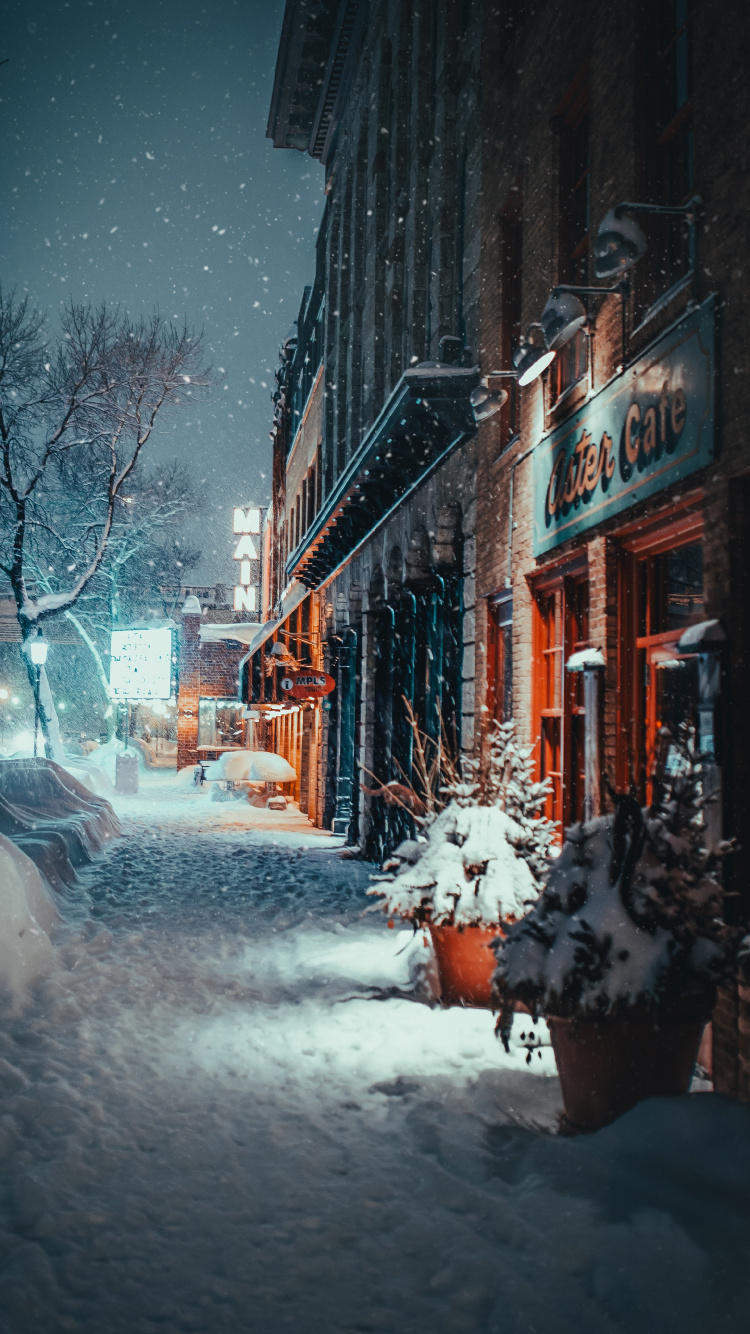 Snow Covered Road Between Buildings During Daytime. Wallpaper in 750x1334 Resolution
