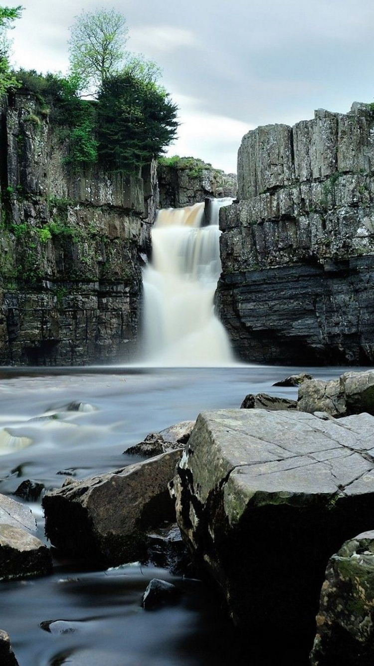 Waterfalls Between Gray Rocky Mountain Under Gray Sky During Daytime. Wallpaper in 750x1334 Resolution