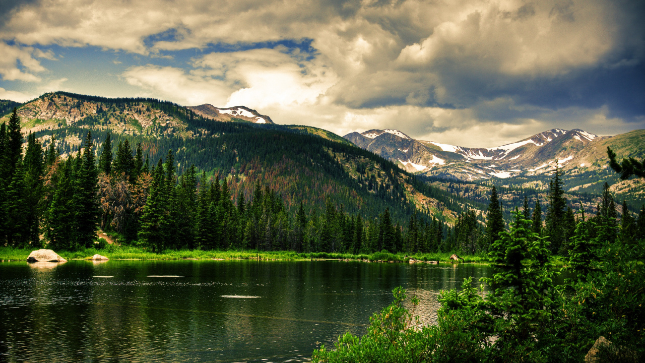 Lac Entouré D'arbres et de Montagnes Sous un Ciel Nuageux Pendant la Journée. Wallpaper in 1280x720 Resolution