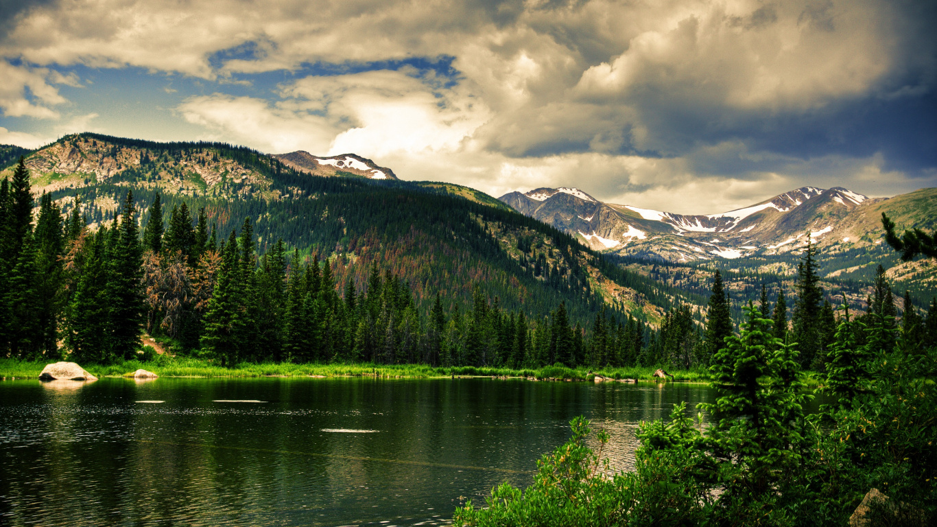 Lac Entouré D'arbres et de Montagnes Sous un Ciel Nuageux Pendant la Journée. Wallpaper in 1366x768 Resolution