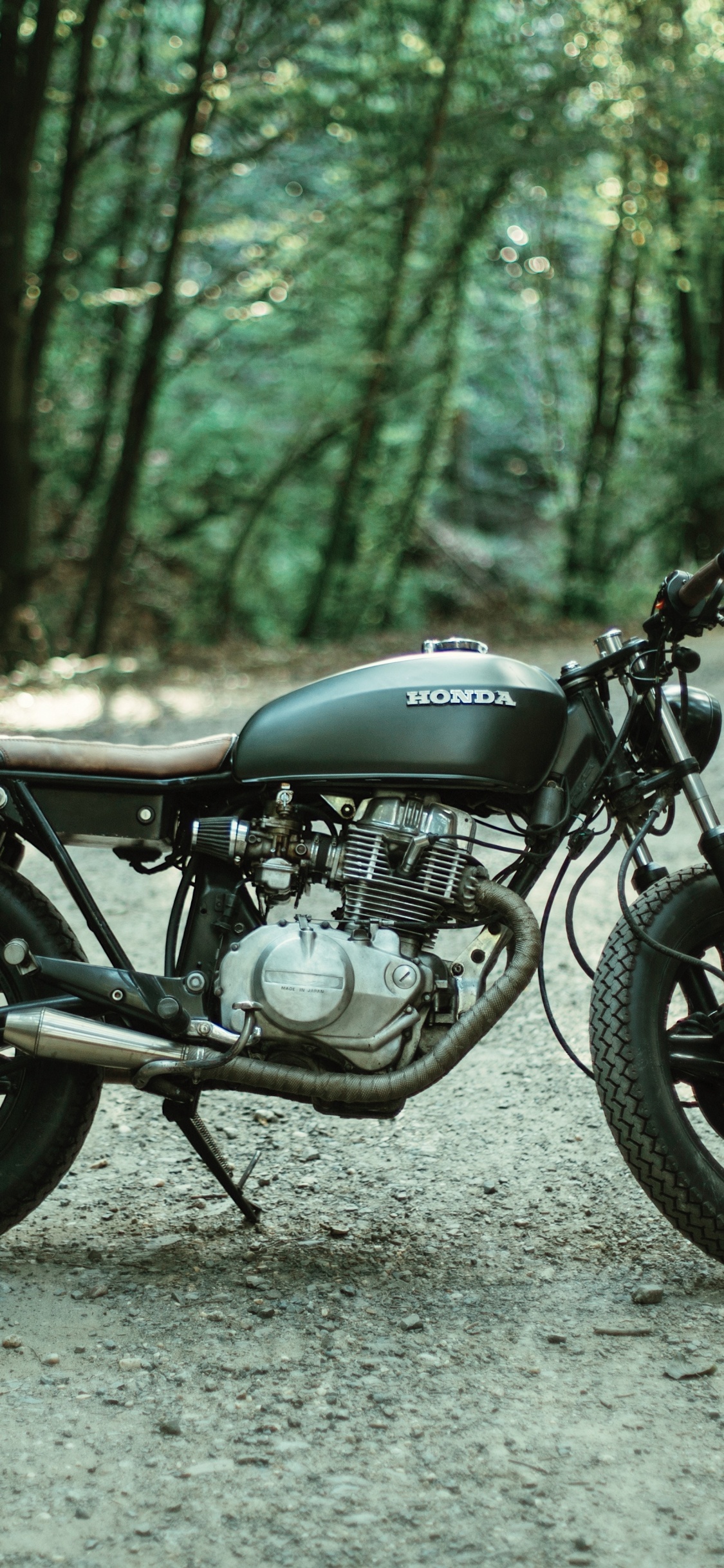 Black Motorcycle Parked on Gray Dirt Road During Daytime. Wallpaper in 1125x2436 Resolution