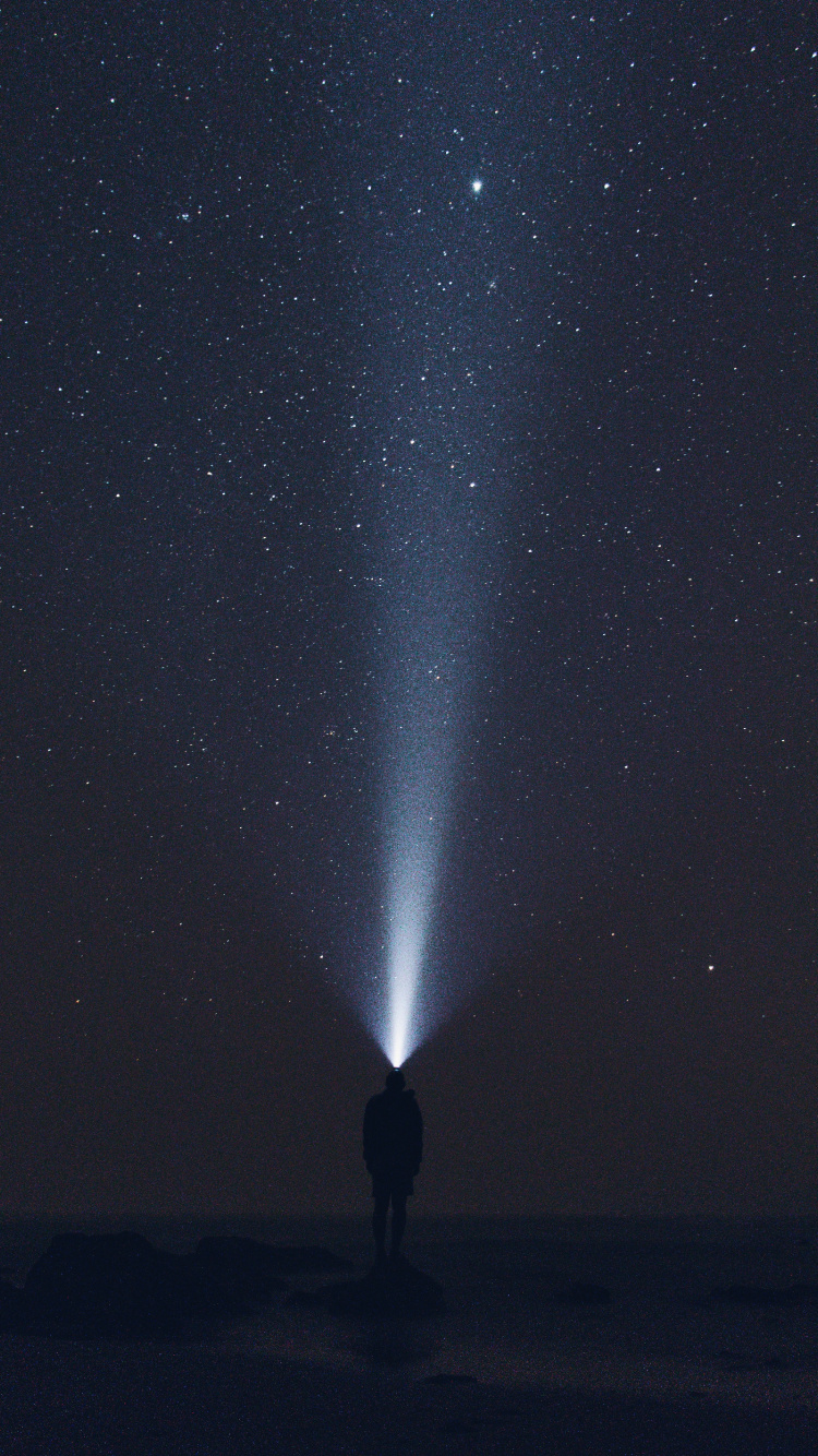 Hombre Con Chaqueta Negra de Pie Bajo la Noche Estrellada. Wallpaper in 750x1334 Resolution