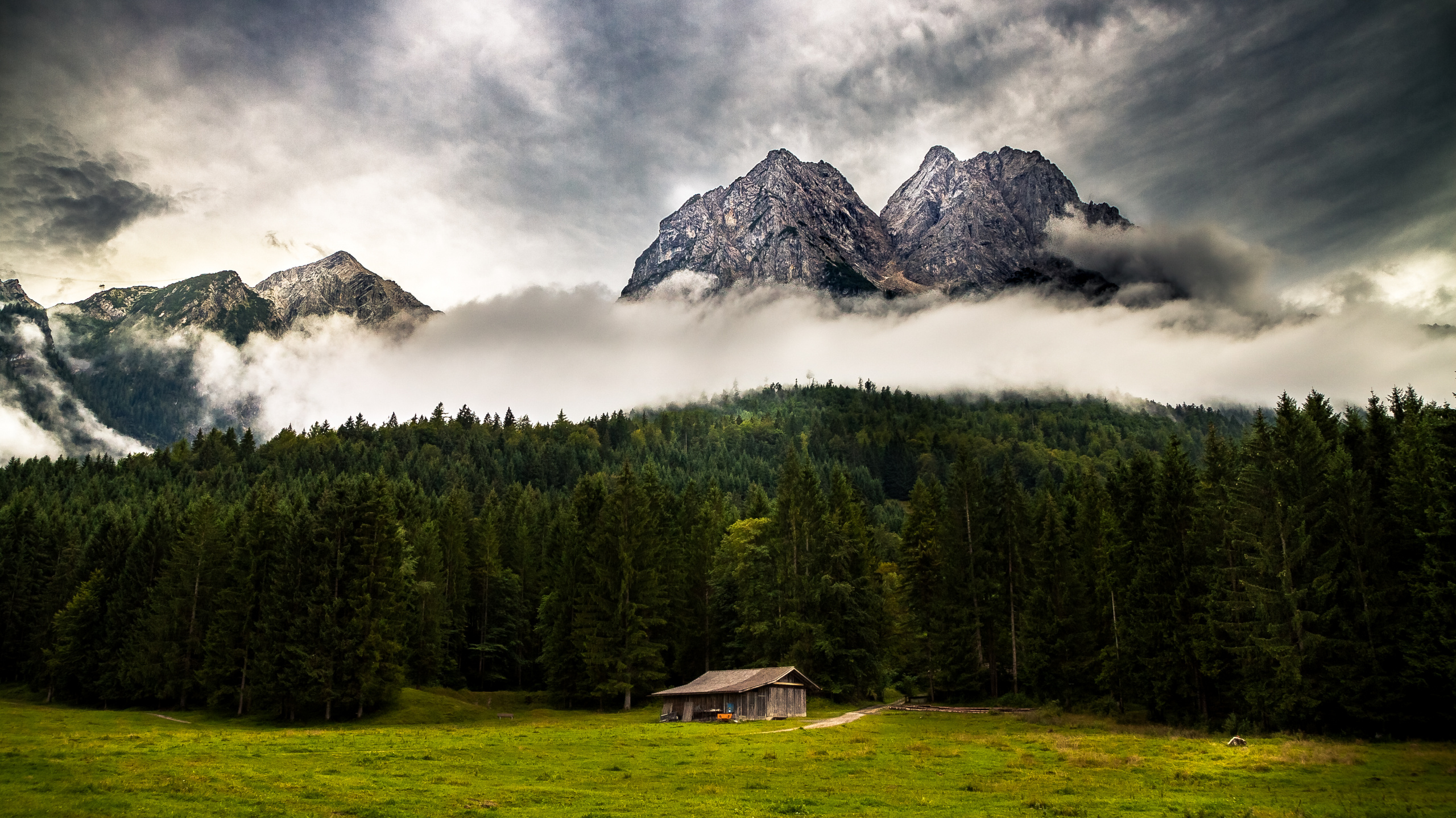 Brown Wooden House on Green Grass Field Near Green Trees and Mountain Under White Clouds During. Wallpaper in 2560x1440 Resolution