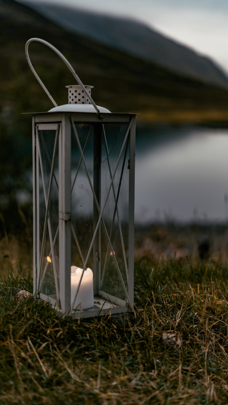 Linterna de Vela Blanca Sobre la Hierba Verde Durante el Día. Wallpaper in 750x1334 Resolution