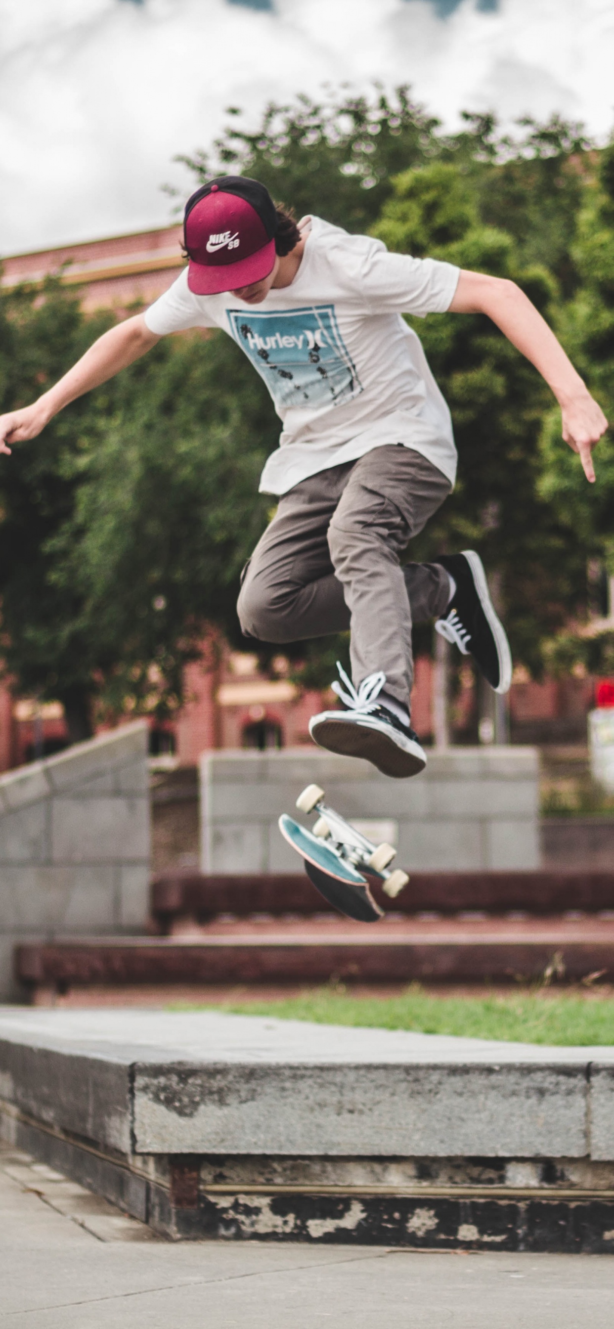 Man in Blue Shirt and Gray Pants Jumping on Brown Concrete Brick During Daytime. Wallpaper in 1242x2688 Resolution