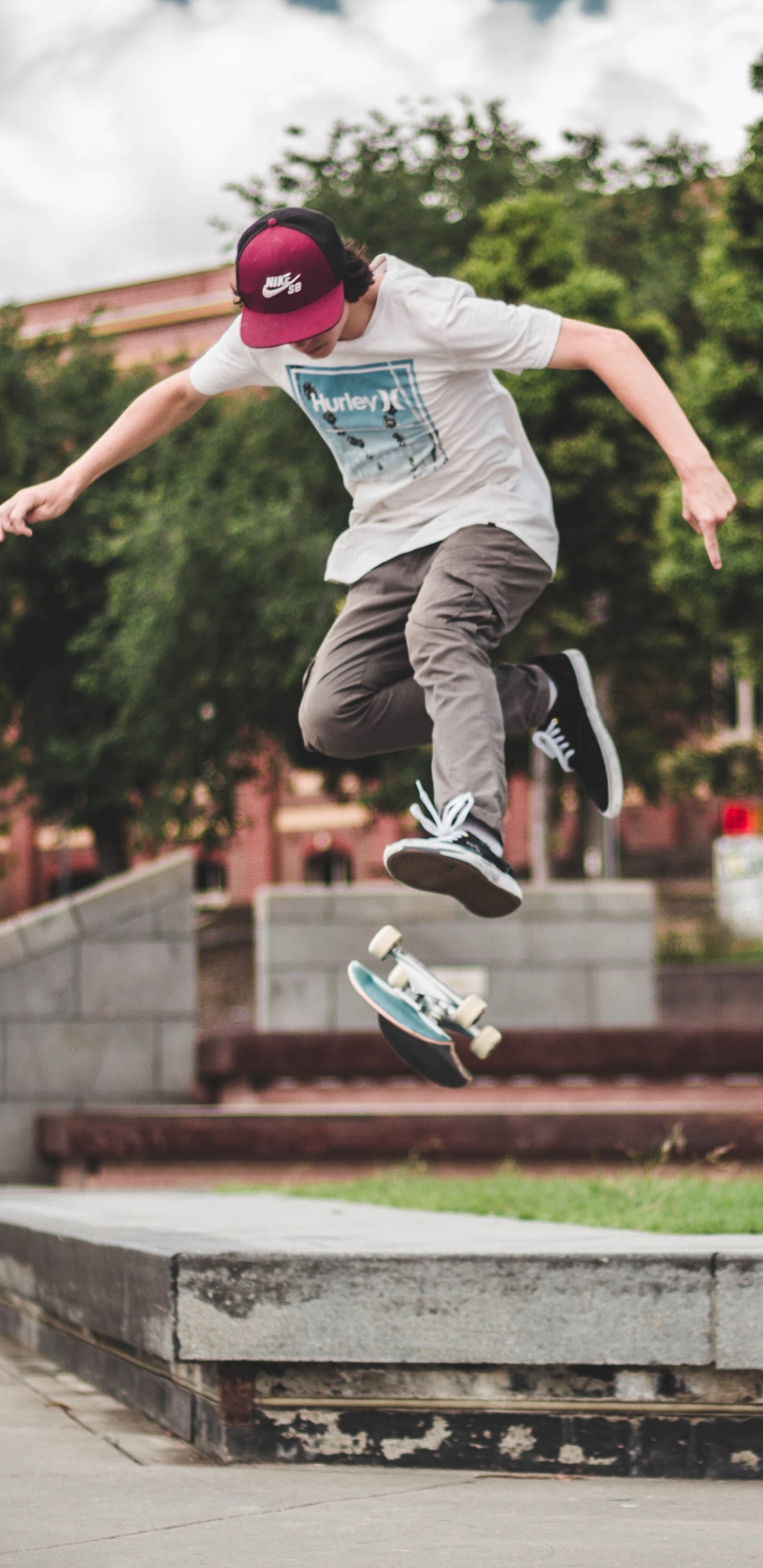 Man in Blue Shirt and Gray Pants Jumping on Brown Concrete Brick During Daytime. Wallpaper in 1440x2960 Resolution
