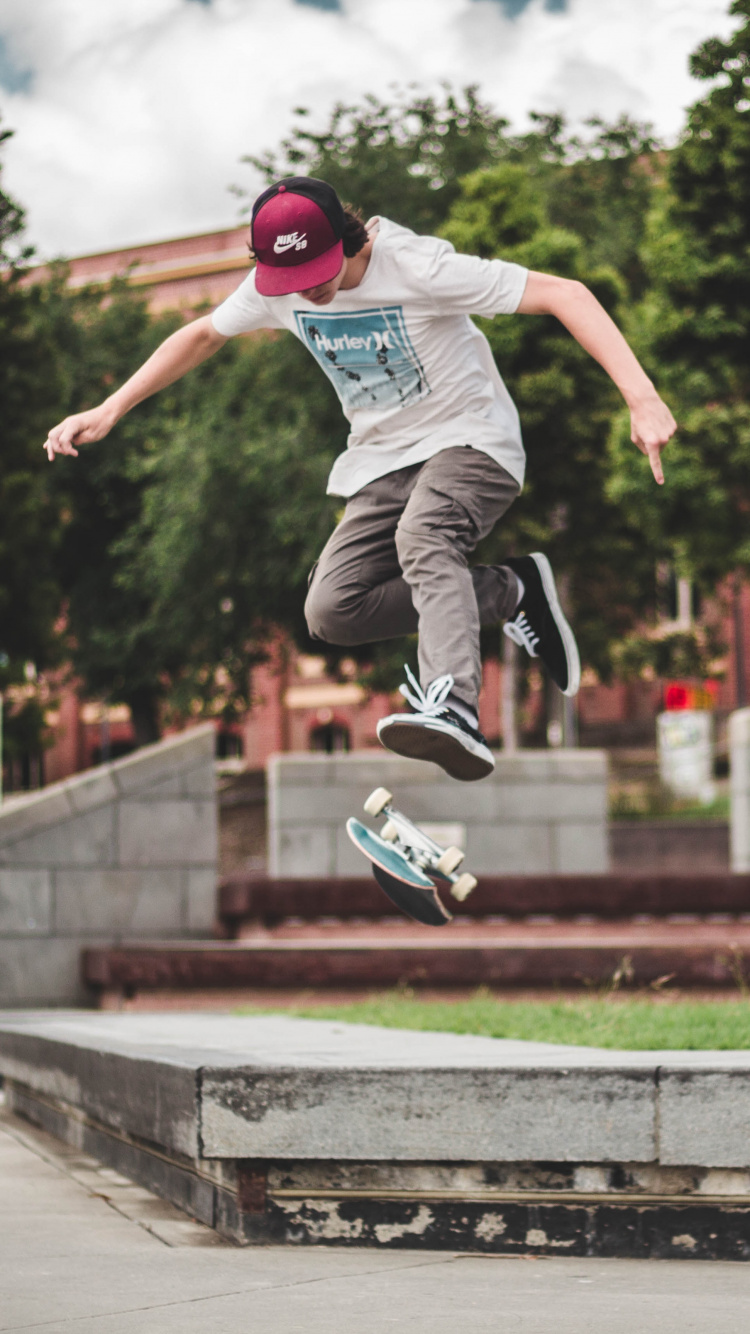 Man in Blue Shirt and Gray Pants Jumping on Brown Concrete Brick During Daytime. Wallpaper in 750x1334 Resolution