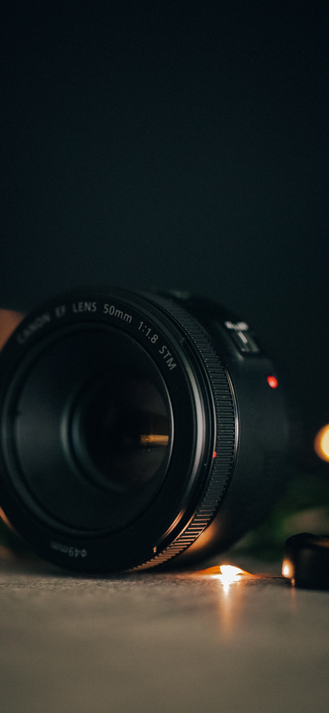 Schwarzes Nikon-Kameraobjektiv Auf Dem Tisch. Wallpaper in 1125x2436 Resolution