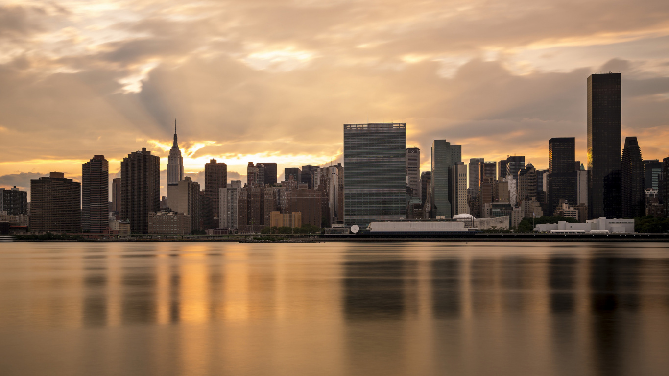 Skyline Der Stadt Über Gewässer Bei Sonnenuntergang. Wallpaper in 1366x768 Resolution