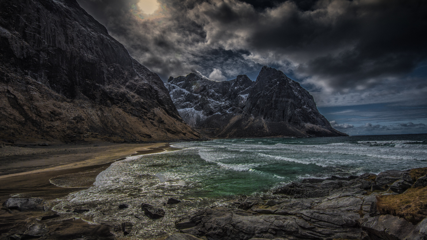 Brown Rocky Mountain Beside Body of Water Under Cloudy Sky During Daytime. Wallpaper in 1366x768 Resolution