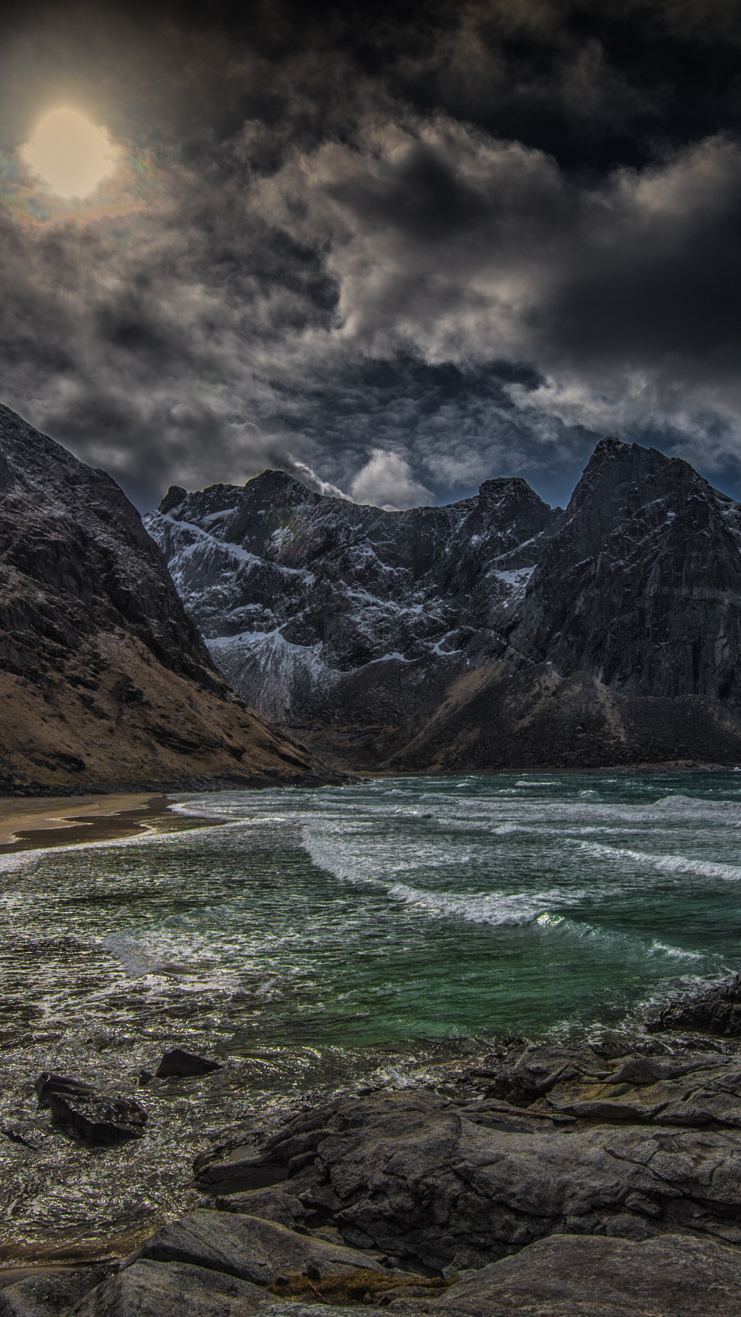 Brown Rocky Mountain Beside Body of Water Under Cloudy Sky During Daytime. Wallpaper in 1440x2560 Resolution
