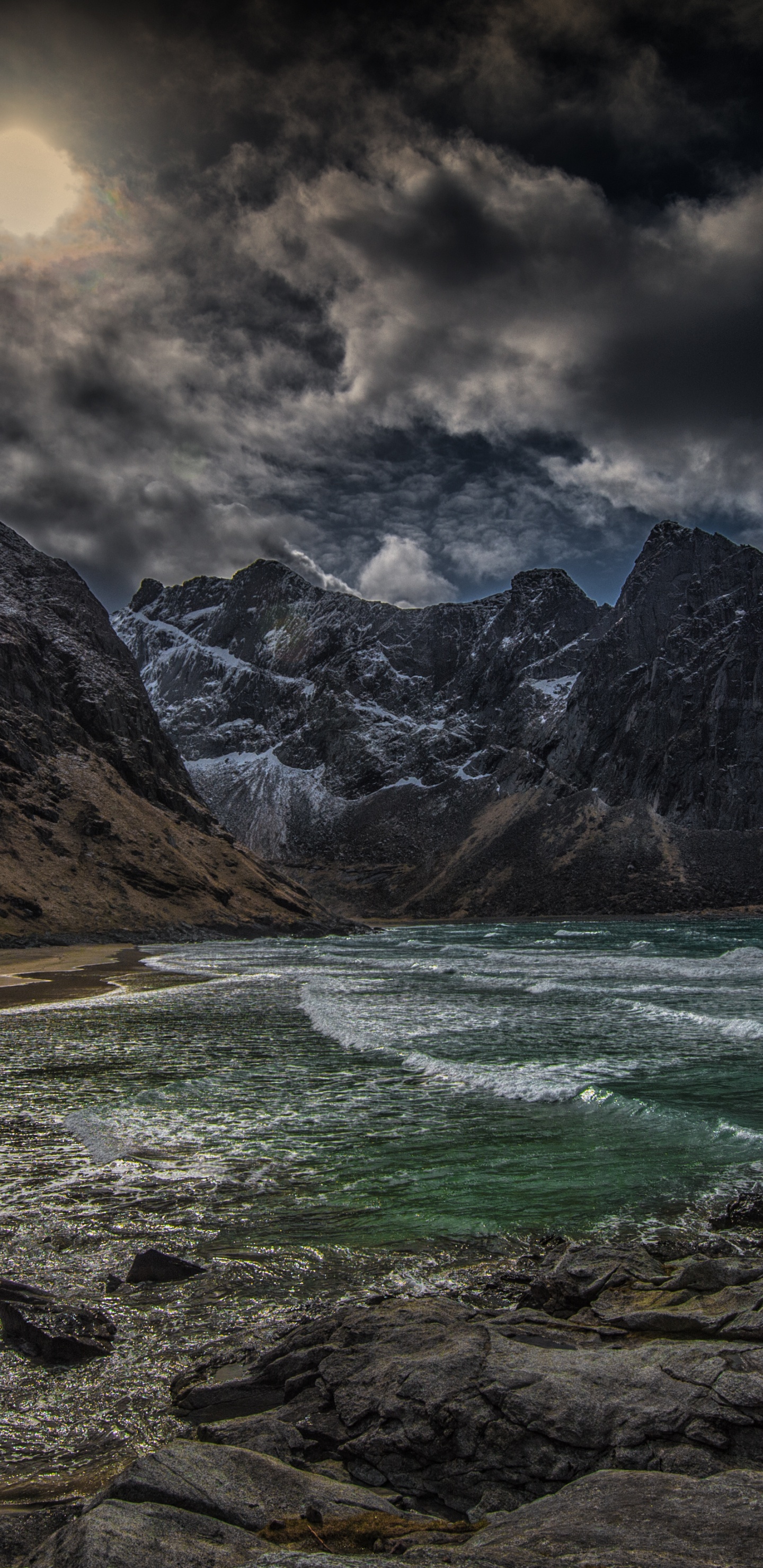Brown Rocky Mountain Beside Body of Water Under Cloudy Sky During Daytime. Wallpaper in 1440x2960 Resolution
