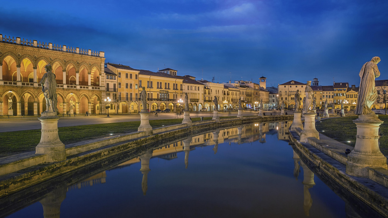 Brown Concrete Building Near Body of Water During Night Time. Wallpaper in 1280x720 Resolution