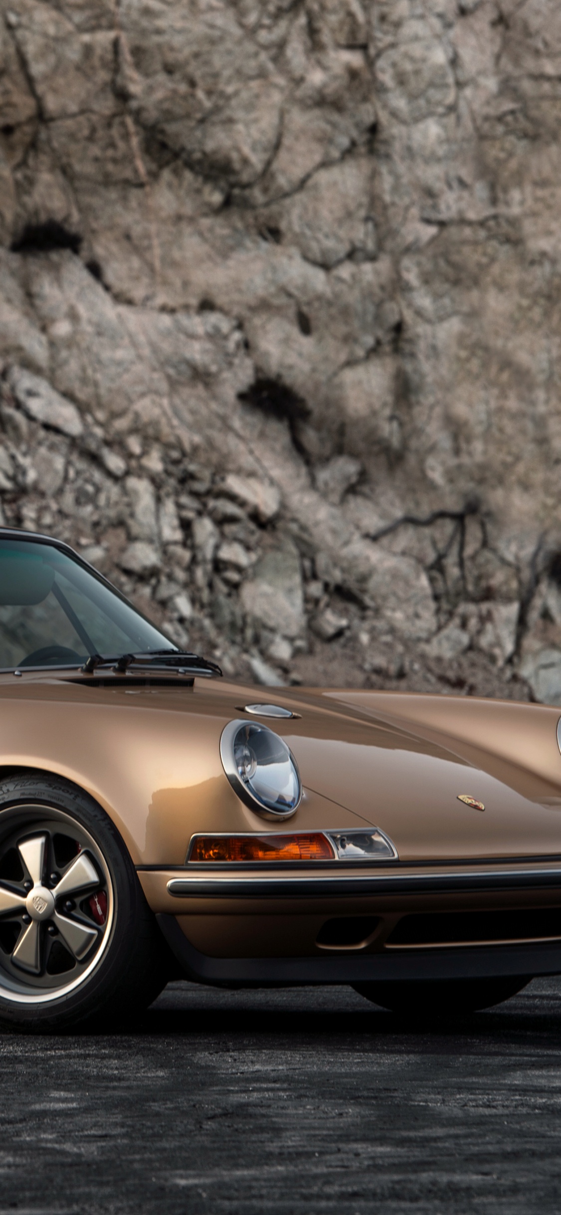 Porsche 911 Naranja Estacionado Cerca de Brown Rock. Wallpaper in 1125x2436 Resolution