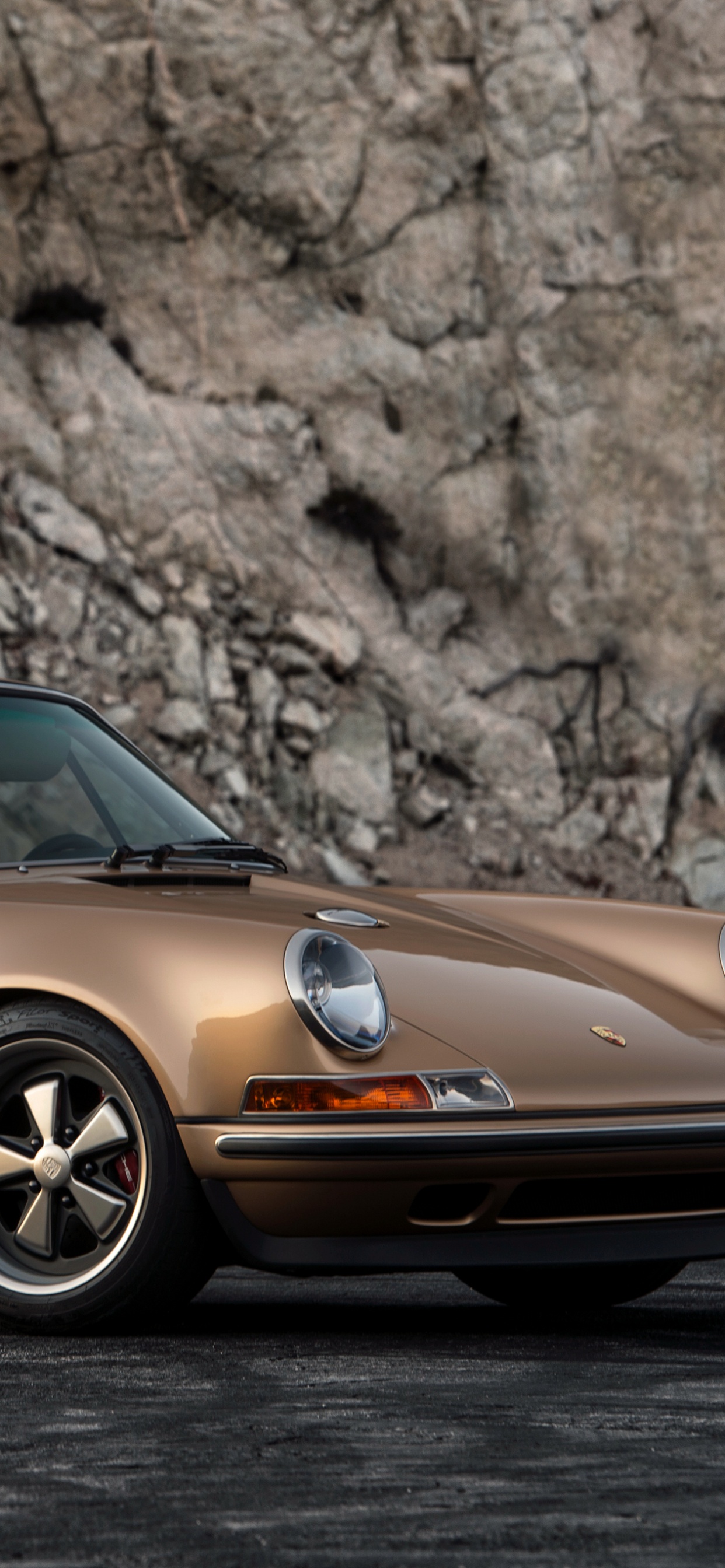 Orange Porsche 911 Parked Near Brown Rock. Wallpaper in 1242x2688 Resolution