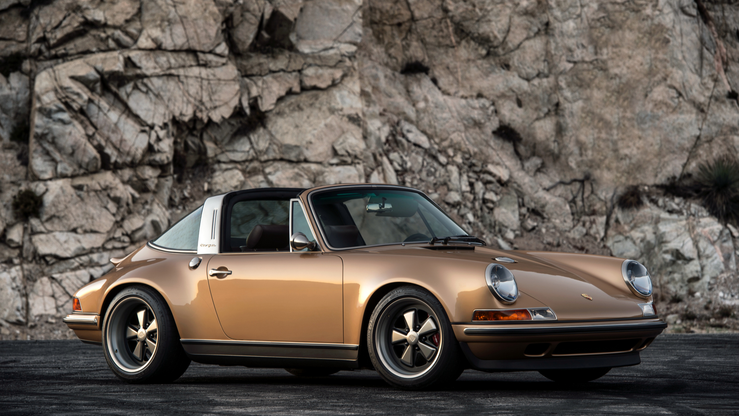 Orange Porsche 911 Parked Near Brown Rock. Wallpaper in 2560x1440 Resolution