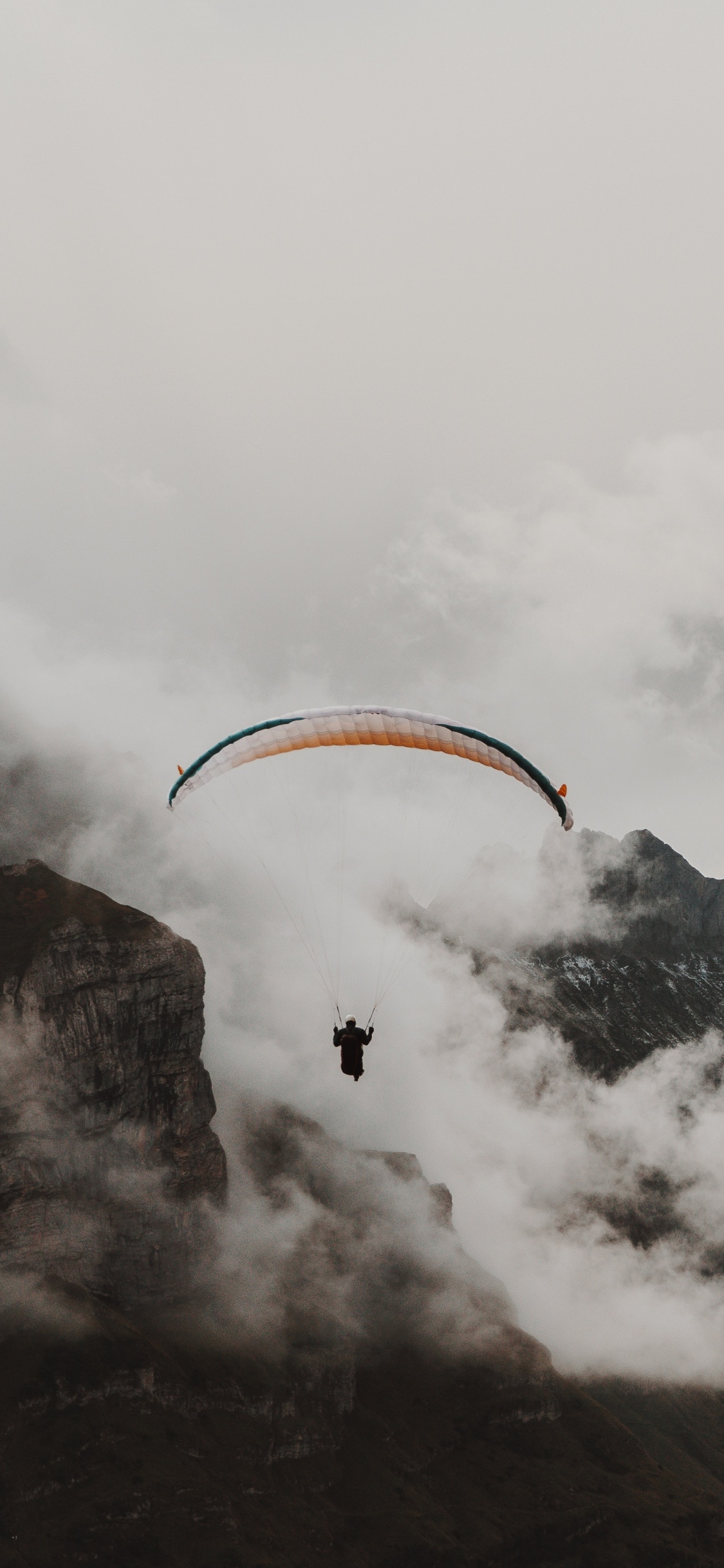 Person Reitet Fallschirm Über Schneebedeckten Berg. Wallpaper in 1125x2436 Resolution