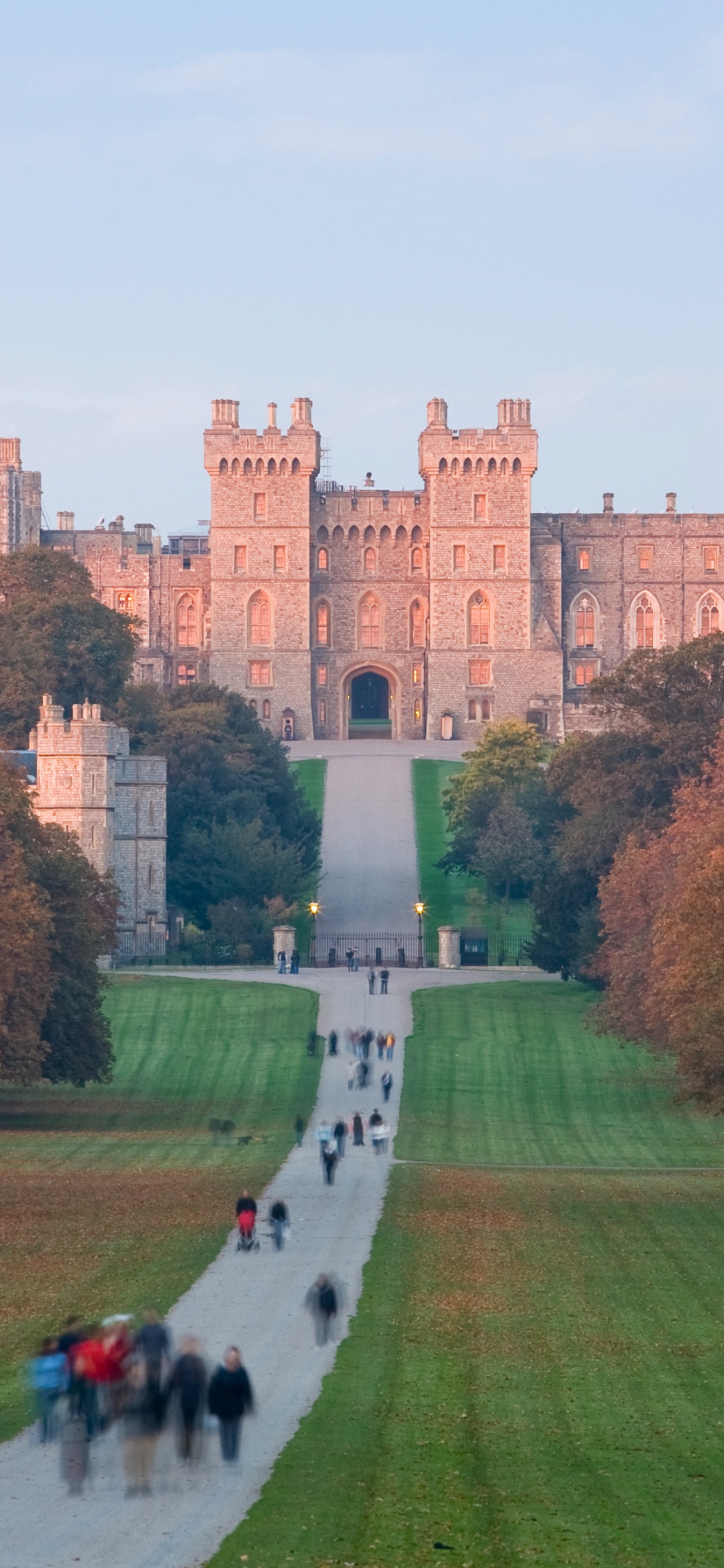 Personnes Marchant Sur un Terrain D'herbe Verte Près D'un Bâtiment en Béton Brun Pendant la Journée. Wallpaper in 1125x2436 Resolution