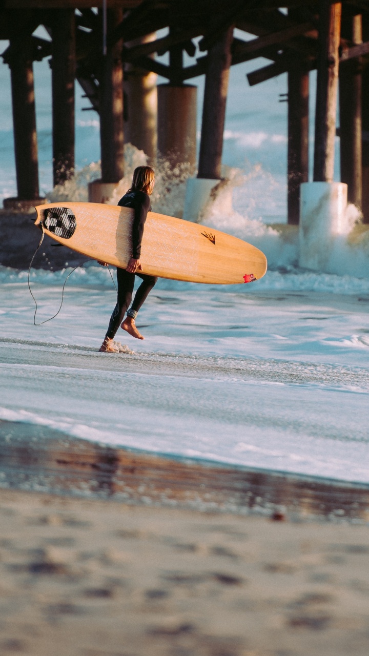 Personne Tenant Une Planche de Surf Blanche Marchant Sur la Plage Pendant la Journée. Wallpaper in 720x1280 Resolution