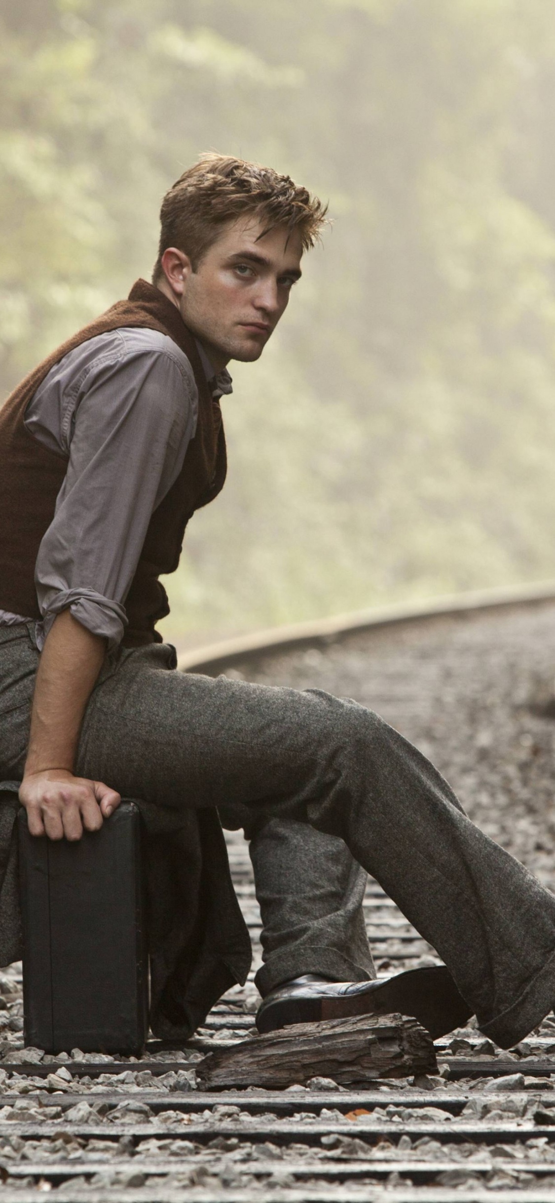 Mann in Lila Hemd Und Schwarzer Denim-Jeans, Der Tagsüber Auf Der Zugschiene Sitzt. Wallpaper in 1125x2436 Resolution