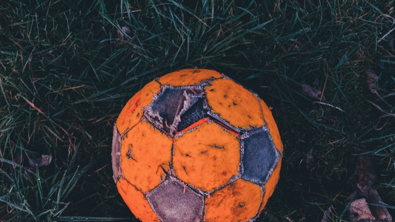 Ballon de Football Orange et Noir Sur L'herbe Verte. Wallpaper in 1280x720 Resolution