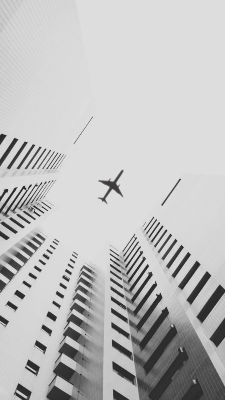 Photo en Niveaux de Gris D'un Avion Dans Les Airs Au-dessus D'un Immeuble de Grande Hauteur. Wallpaper in 720x1280 Resolution
