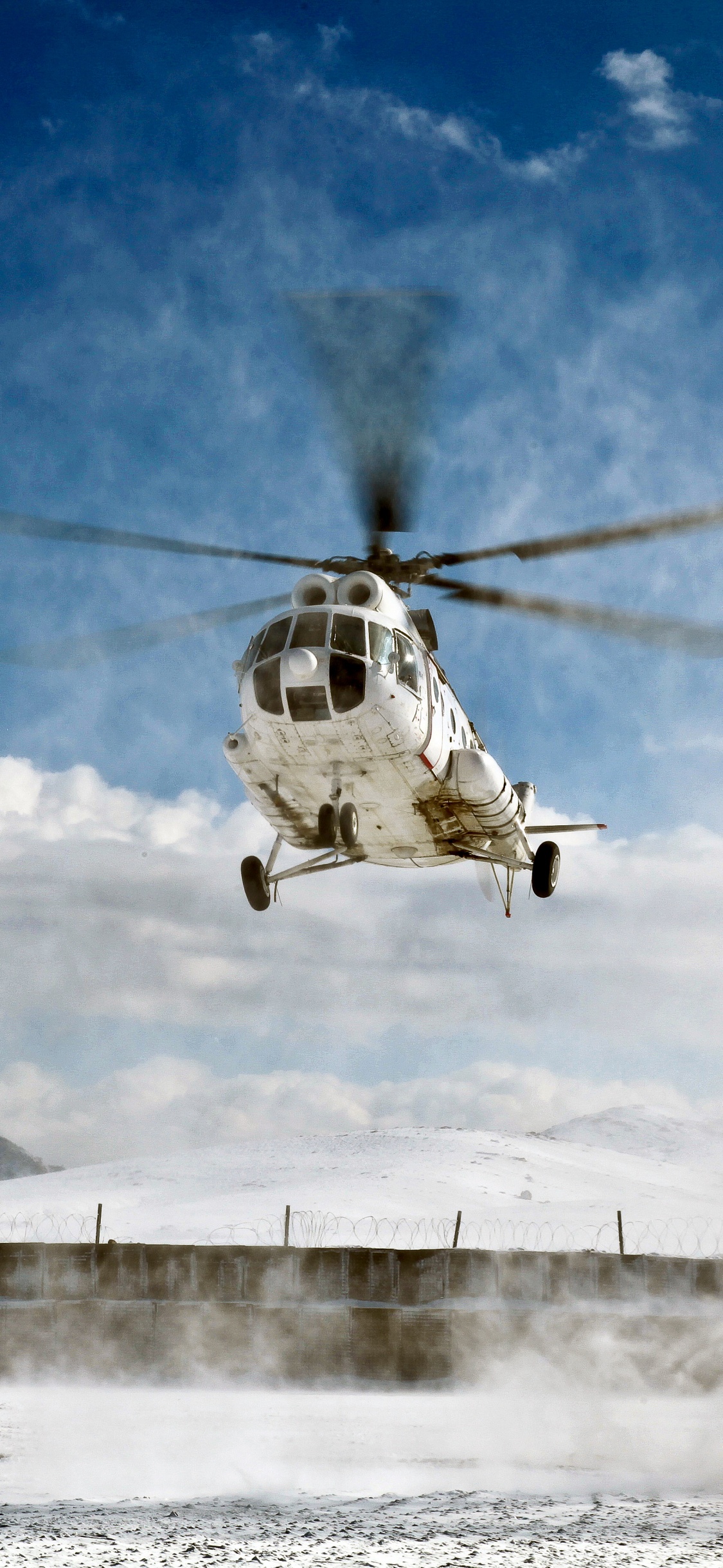 Helicóptero Blanco y Negro Sobrevolando Montañas Cubiertas de Nieve Durante el Día. Wallpaper in 1125x2436 Resolution