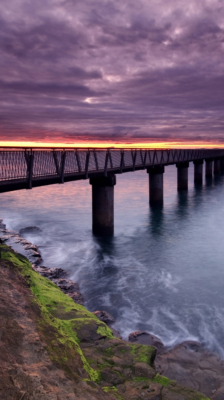 Brown Wooden Bridge Over The Sea Under Gray Clouds. Wallpaper in 750x1334 Resolution