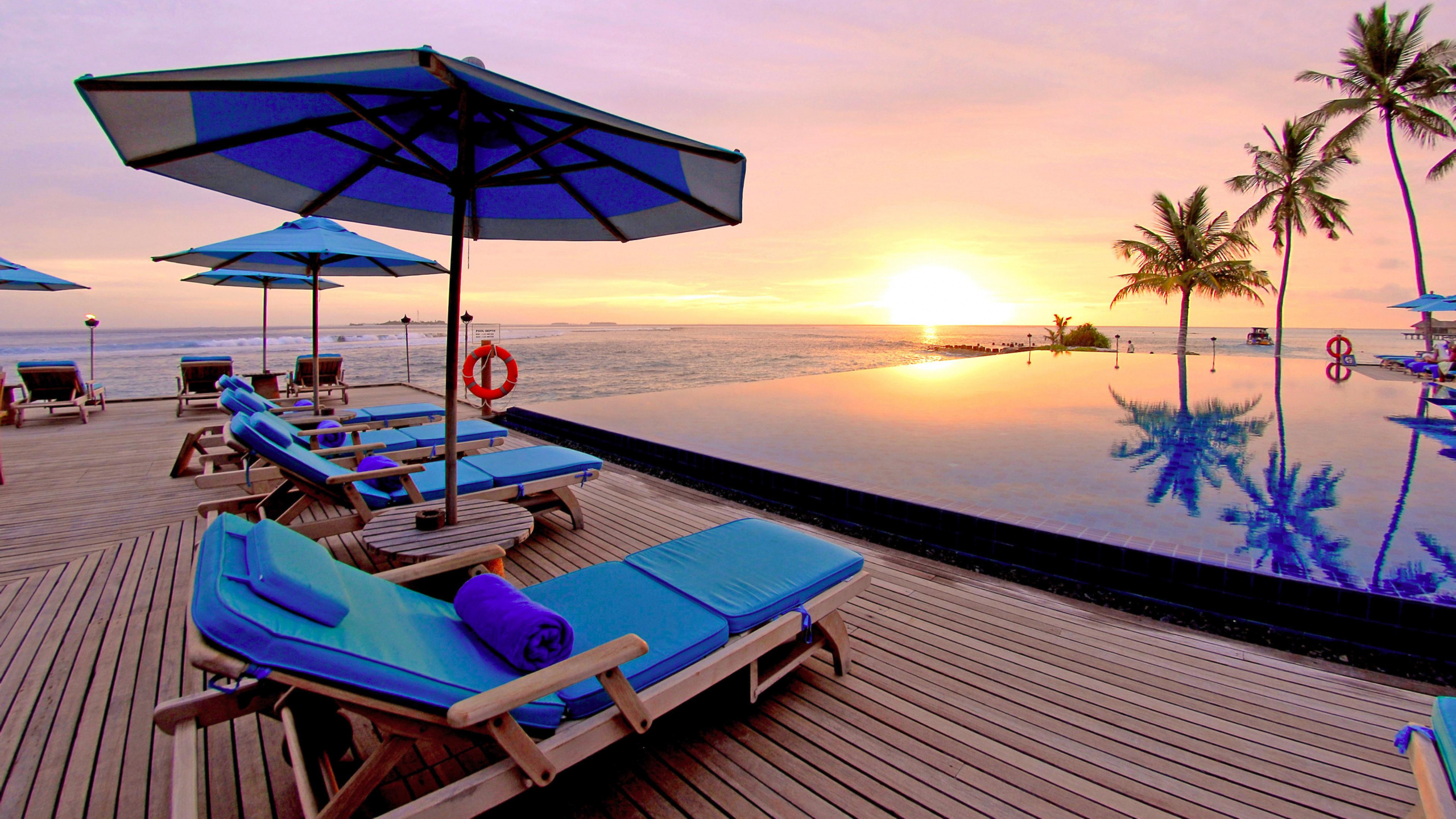 Chaises Longues Bleues et Blanches Sur la Plage Pendant le Coucher du Soleil. Wallpaper in 2560x1440 Resolution