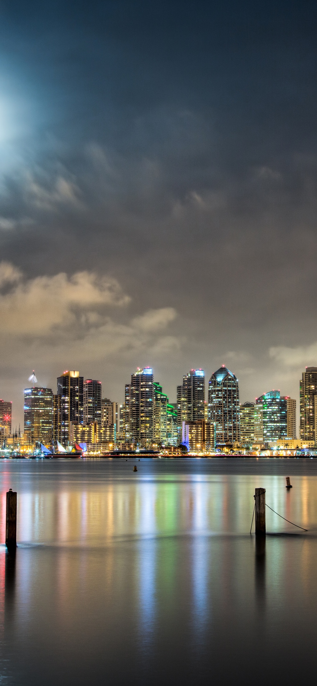 Skyline Der Stadt Über Gewässer Während Der Nacht. Wallpaper in 1242x2688 Resolution