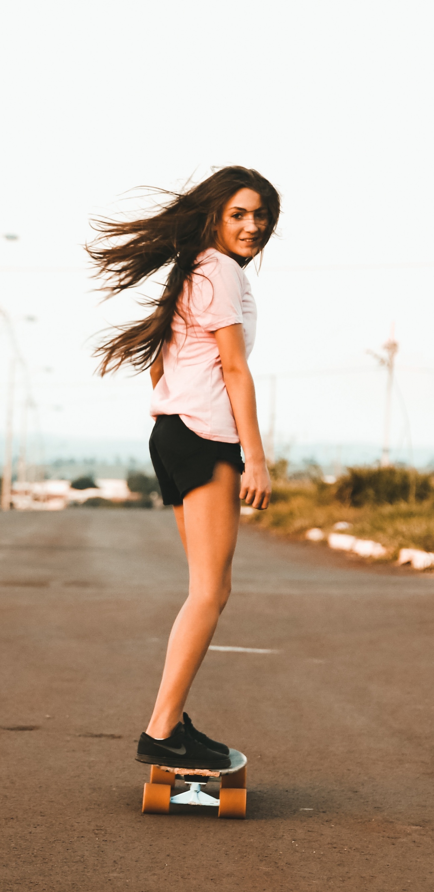 Woman in White Tank Top and Black Shorts Standing on Road During Daytime. Wallpaper in 1440x2960 Resolution
