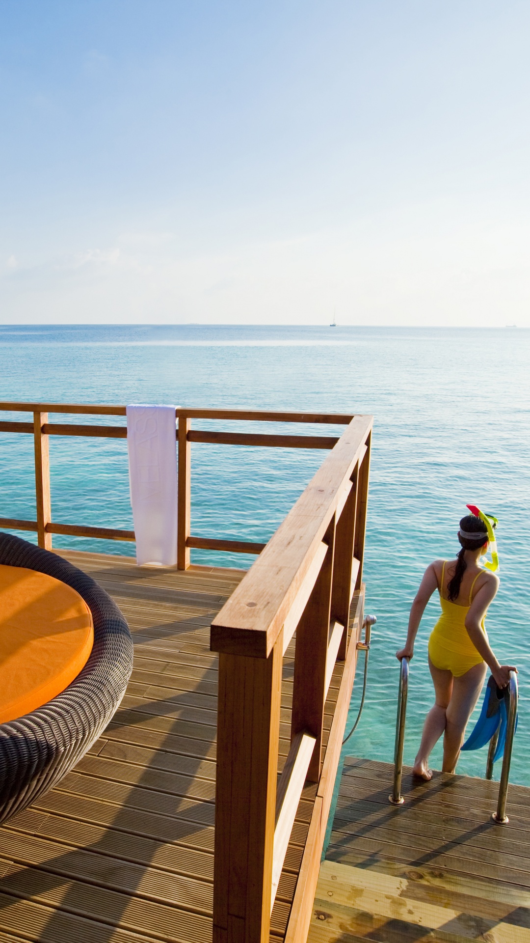 Woman in Blue Bikini Sitting on Brown Wooden Bench Near Sea During Daytime. Wallpaper in 1080x1920 Resolution