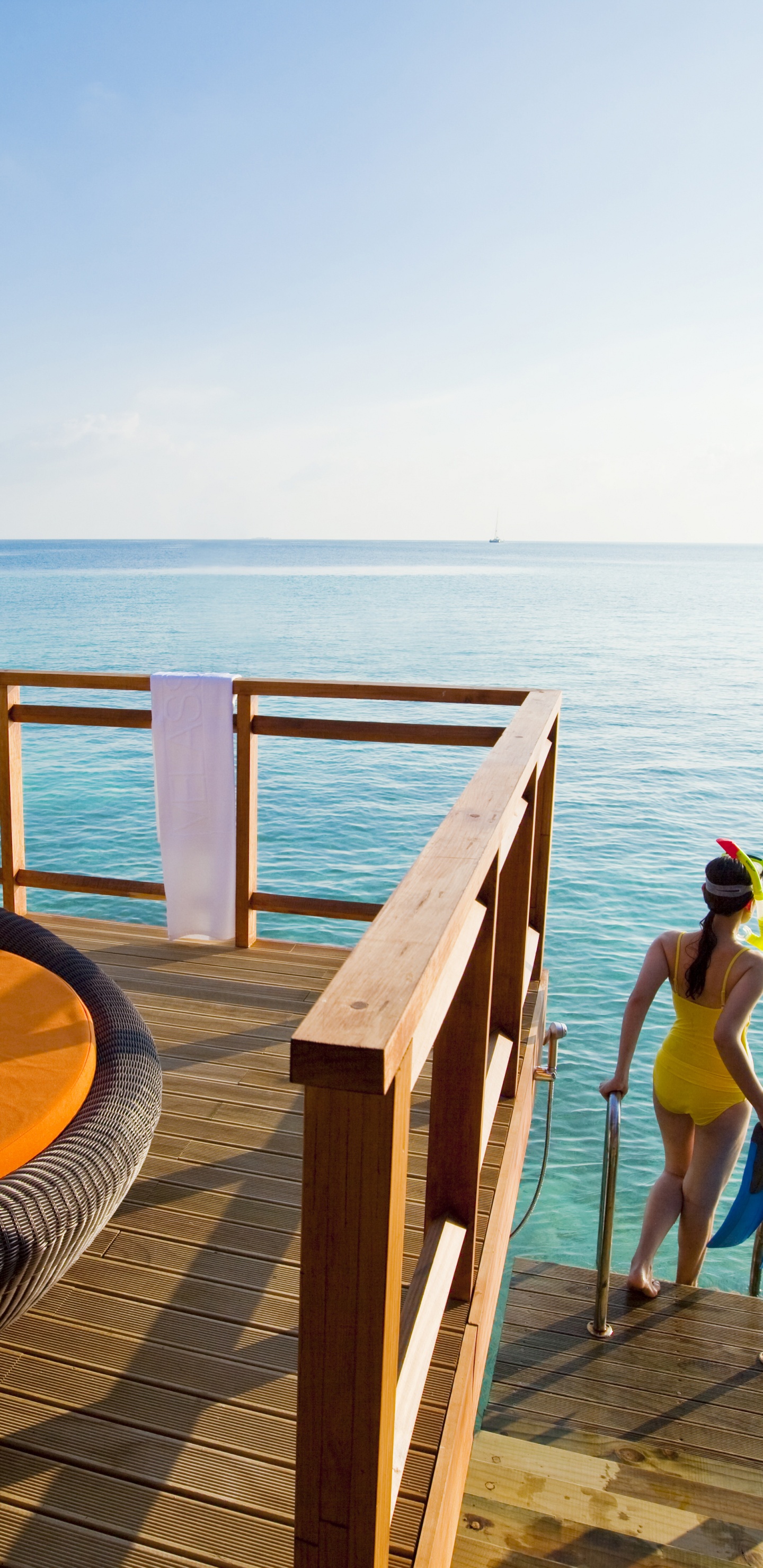 Woman in Blue Bikini Sitting on Brown Wooden Bench Near Sea During Daytime. Wallpaper in 1440x2960 Resolution