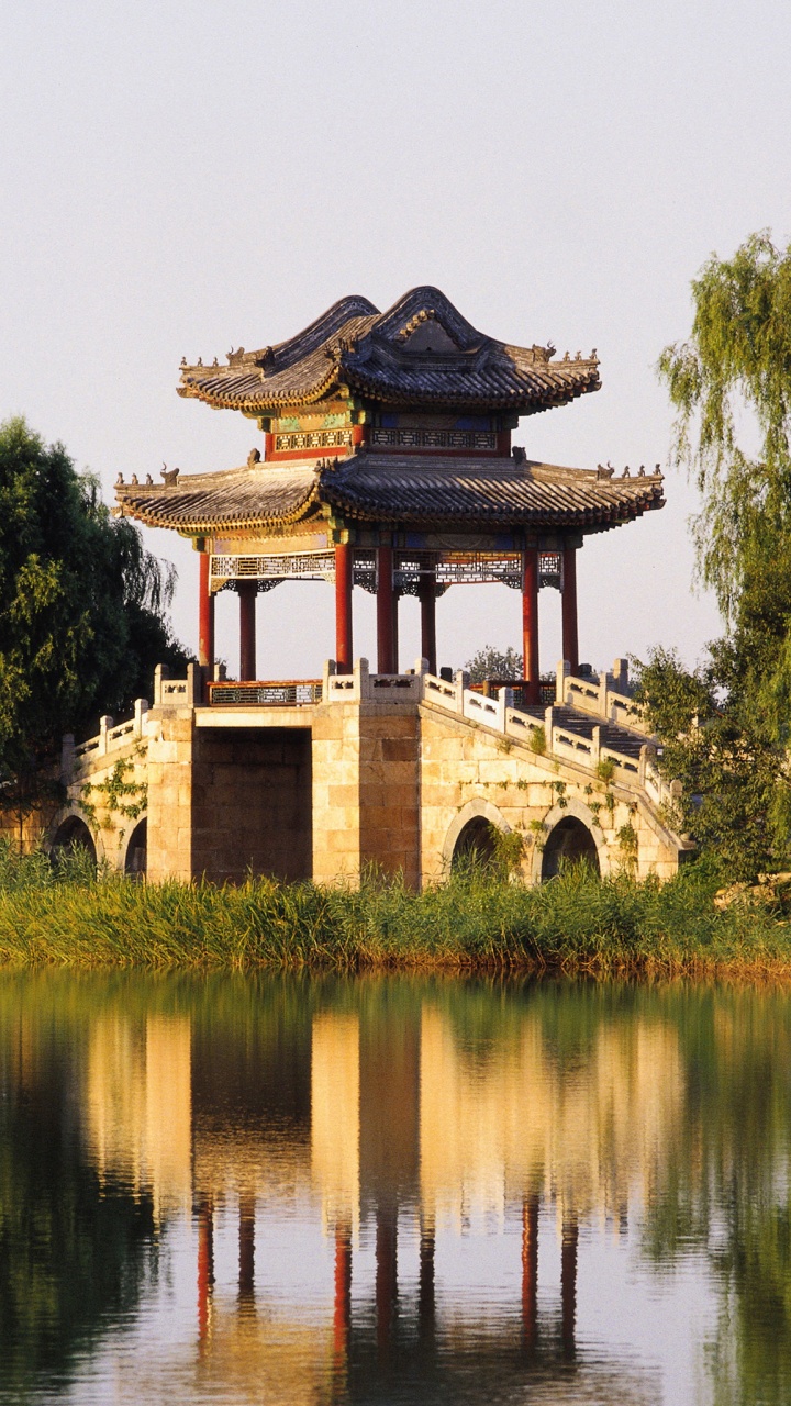 Brown and Black Concrete Building Near Green Trees and Lake During Daytime. Wallpaper in 720x1280 Resolution