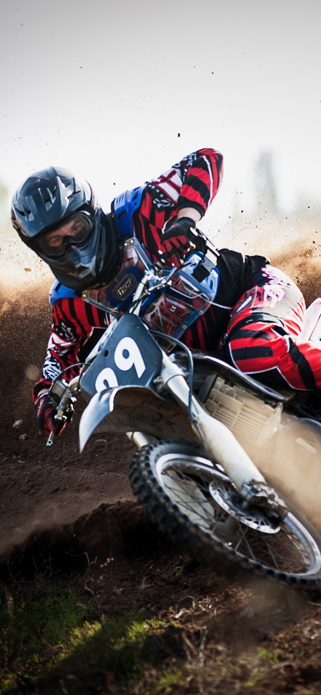 Hombre Montando Motocross Dirt Bike en Camino de Tierra Durante el Día. Wallpaper in 1125x2436 Resolution