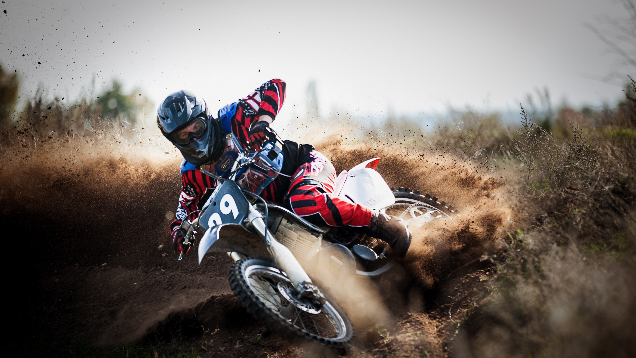 Man Riding Motocross Dirt Bike Sur Chemin de Terre Pendant la Journée. Wallpaper in 2560x1440 Resolution